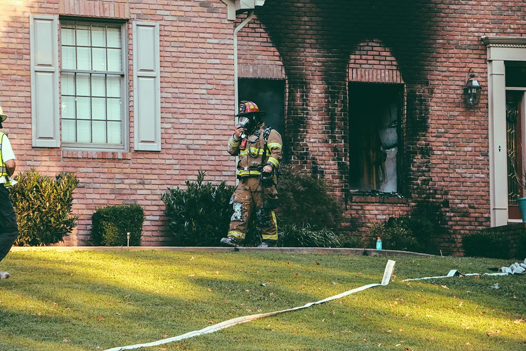 Fire fighter walking out of burnt house